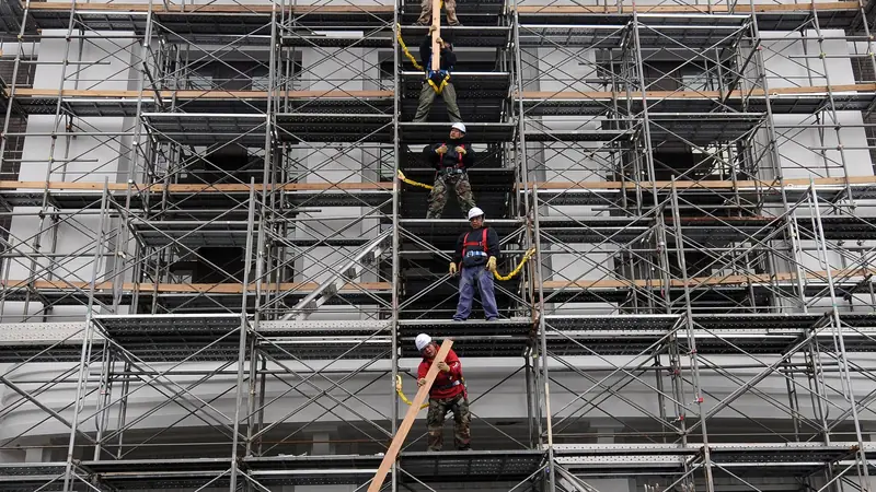 Fassade streichen in Basel: Arbeiter bauen ein Fassadengerüst an einem mehrstöckigen Gebäude ab